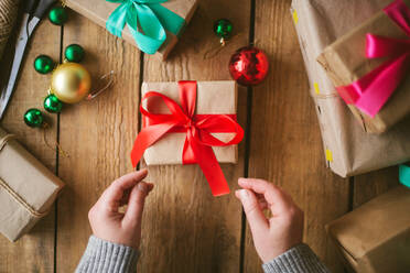 Woman wrapping christmas gifts on wooden background - CAVF73697