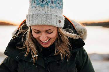 Portrait of woman with snow in her hair laughing at sunset - CAVF73738