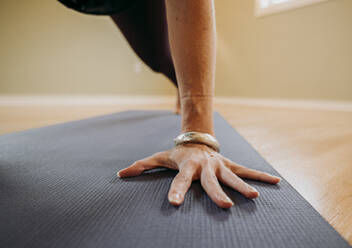 Nahaufnahme einer weiblichen Hand mit Armband auf einer Yogamatte in einem Studio - CAVF73804