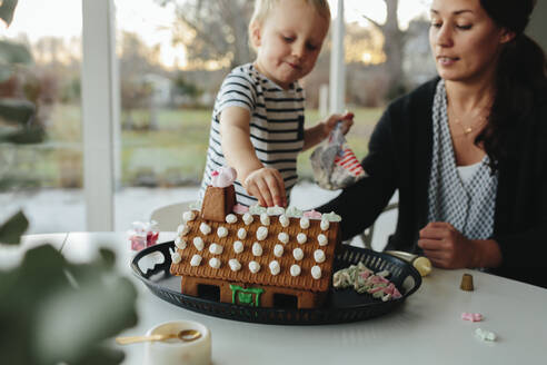 Mutter mit Sohn beim Bau eines Lebkuchenhauses - JOHF06645