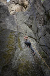 Young woman climbing rock wall - JOHF06814