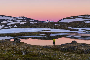 Person standing by lake in mountains - JOHF06907