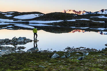 Person standing by lake in mountains - JOHF06908