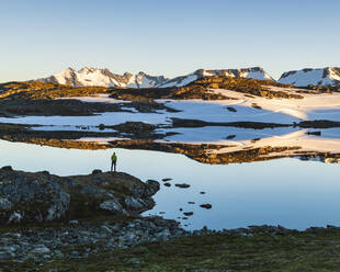 Person stehend am See in den Bergen - JOHF06915