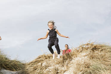 Girl jumping on sand dune - JOHF06924