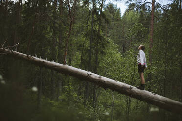 Girl standing on fallen tree - JOHF06950