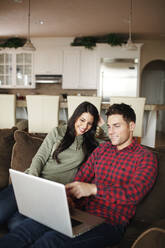 Ehepaar benutzt Laptop im Wohnzimmer - CAVF73857