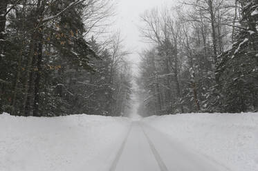 Eine geräumte einspurige Straße während eines Schneesturms in New Hampshire. - CAVF73867