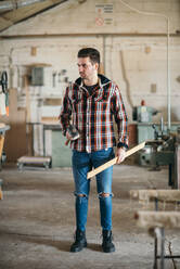 A young carpenter holding hammer and wooden board - CAVF73898