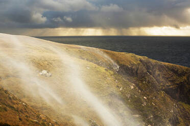 Wasserfälle des Moorlandbachs an der Küste bei Stoer in Assynt, Schottland, Vereinigtes Königreich, die bei stürmischen Winden bergauf wehen. - CAVF73907