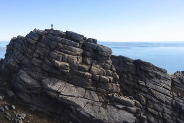 Silhouette einer Person auf gestapelten Felsen über dem Meer - CAVF73986