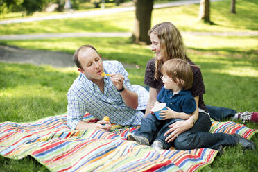 Family blowing bubbles with son in the park - CAVF74043