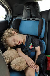Kleiner Junge schläft in seinem Autositz mit seinem Lieblingskuscheltier - CAVF74141