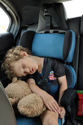 Little boy asleep in his car seat with his favorite stuffed toy - CAVF74141