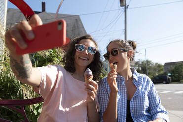 Zwei Frauen machen ein Selfie, während sie Eiscreme essen. - CAVF74215