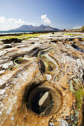 Felsformationen und Seegras in der Bucht von Laig bei Cleadale auf der Isle of Eigg, mit Blick auf die Isle of Rhum, Schottland, Vereinigtes Königreich. - CAVF74220