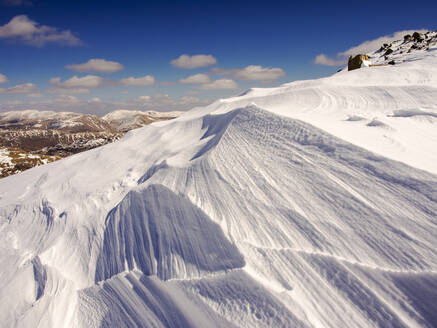 Vom starken Wind geformter und aufgewirbelter Schnee oberhalb des Wrynose Passes im Lake District, Cumbria, Großbritannien. - CAVF74224