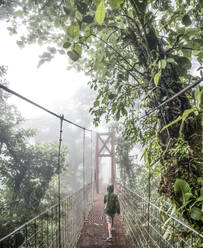 Ein Junge geht über eine Brücke im Nebelwald von Monteverde - CAVF74268