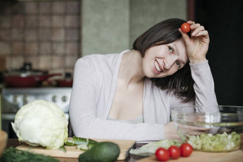 Porträt einer glücklichen Frau, die in der Küche einen Salat zubereitet - EYAF00913
