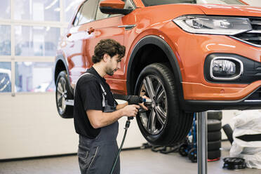 Automechaniker in einer Werkstatt beim Reifenwechsel - MOEF02724