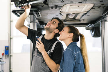 Automechaniker im Gespräch mit einem Kunden in der Werkstatt - MOEF02729