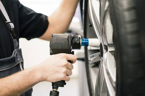 Nahaufnahme eines Automechanikers in einer Werkstatt beim Reifenwechsel - MOEF02730