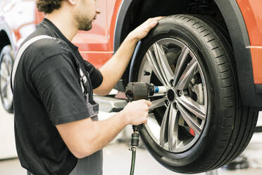 Automechaniker in einer Werkstatt beim Reifenwechsel - MOEF02731