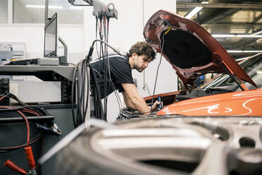 Car mechanic in a workshop working at car - MOEF02734