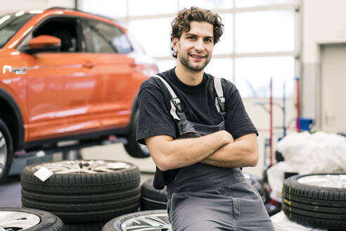 Porträt eines lächelnden Automechanikers in einer Werkstatt - MOEF02736