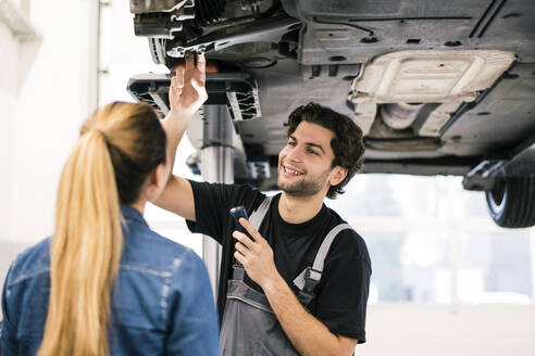 Car mechanic talking to client in workshop - MOEF02743