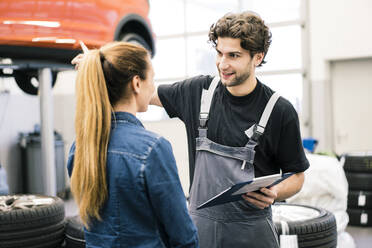 Automechaniker im Gespräch mit einem Kunden in der Werkstatt - MOEF02746