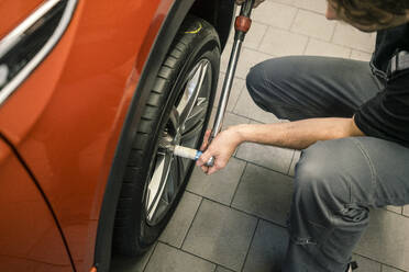 Close-up of car mechanic in a workshop changing tire - MOEF02750