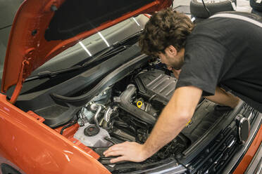 Automechaniker in einer Werkstatt bei der Arbeit am Auto - MOEF02751