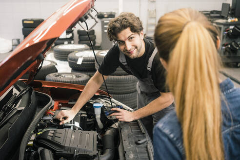 Automechaniker betrachtet einen Kunden in der Werkstatt - MOEF02755