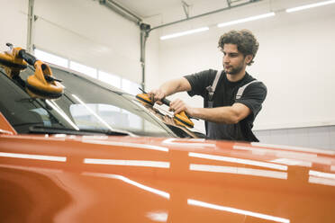 Car mechanic in a workshop changing car window - MOEF02756