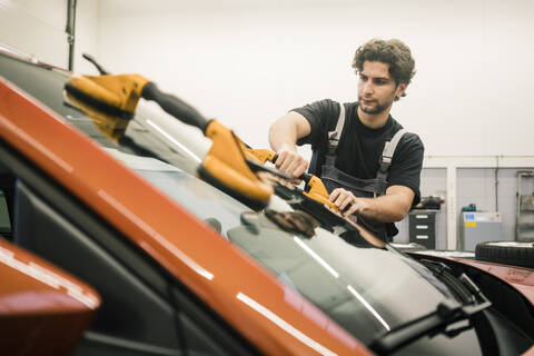 Automechaniker in einer Werkstatt wechselt Autofenster, lizenzfreies Stockfoto