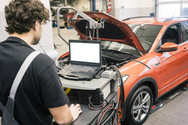 Automechaniker in einer Werkstatt mit modernen Diagnosegeräten - MOEF02763