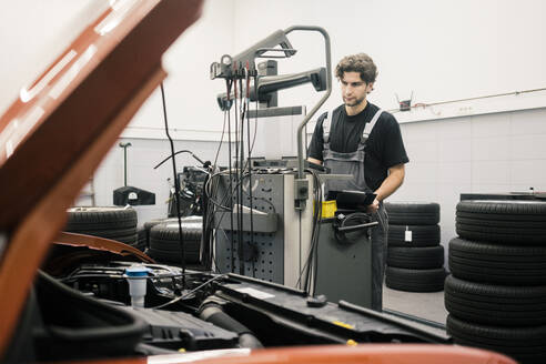 Automechaniker in einer Werkstatt mit modernen Diagnosegeräten - MOEF02764