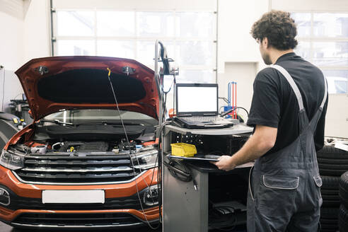 Automechaniker in einer Werkstatt mit modernen Diagnosegeräten - MOEF02765