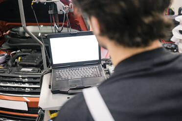 Car mechanic in a workshop using laptop - MOEF02766