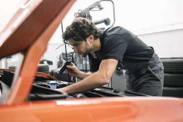 Automechaniker in einer Werkstatt bei der Arbeit am Auto - MOEF02767