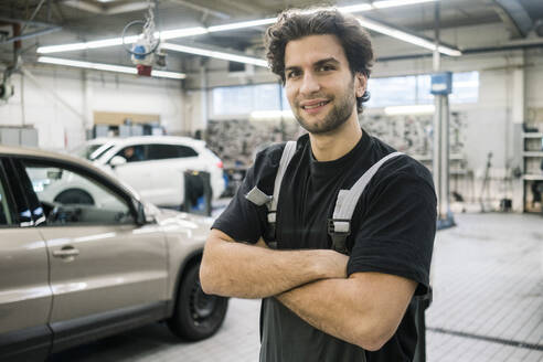 Porträt eines lächelnden Automechanikers in einer Werkstatt - MOEF02771