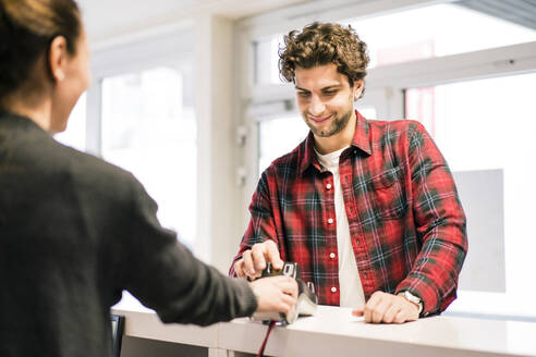 Mann beim Bezahlen mit Kreditkarte an der Kasse eines Geschäfts - MOEF02791