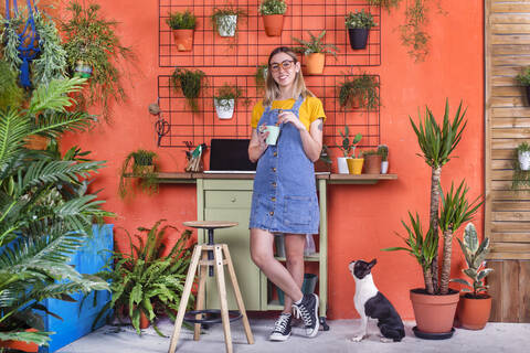 Porträt einer jungen Frau mit Hund auf ihrer Terrasse, lizenzfreies Stockfoto