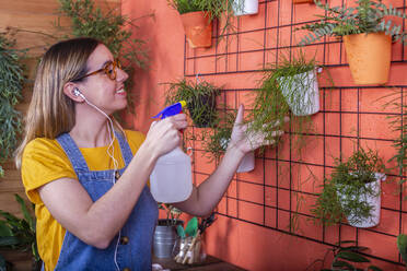 Frau besprüht die Rhipsalis-Pflanze auf ihrer Terrasse mit Wasser - RTBF01417