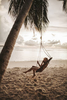 Woman on a swing at the sea at sunset, Maguhdhuvaa Island, Gaafu Dhaalu Atoll, Maldives - DAWF01230