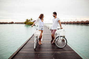 Couple with bicycles on a jetty in the sea, Maguhdhuvaa Island, Gaafu Dhaalu Atoll, Maldives - DAWF01234