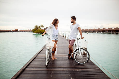 Ehepaar mit Fahrrädern auf einem Steg im Meer, Insel Maguhdhuvaa, Gaafu Dhaalu Atoll, Malediven - DAWF01234