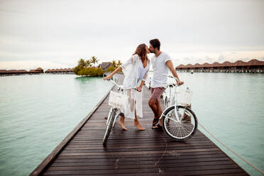 Couple with bicycles kissing on a jetty in the sea, Maguhdhuvaa Island, Gaafu Dhaalu Atoll, Maldives - DAWF01235