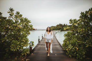 Frau, die auf einem Steg im Meer spazieren geht, Insel Maguhdhuvaa, Gaafu Dhaalu Atoll, Malediven - DAWF01236